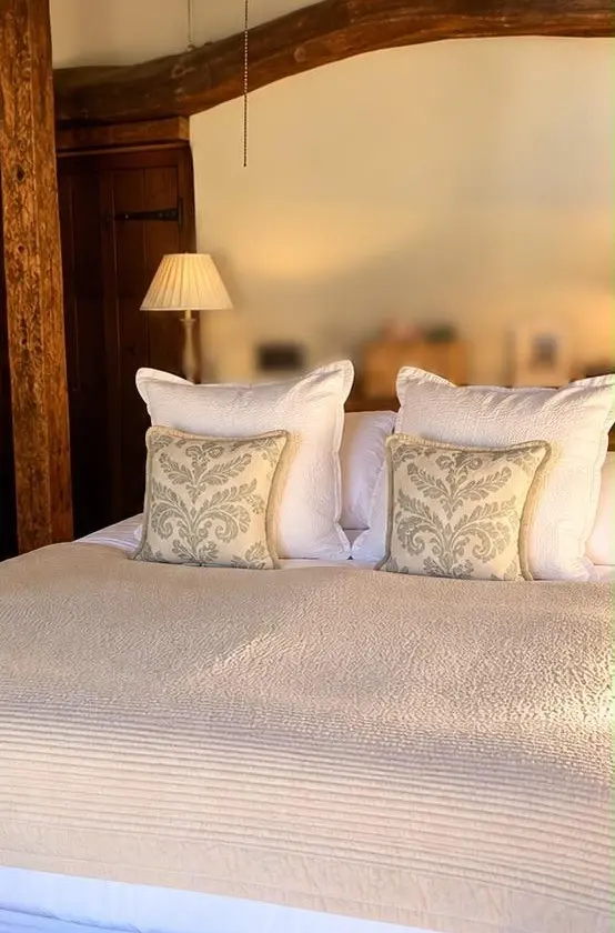 A freshly made bed with clean white linen and cushions, from one of our jobs